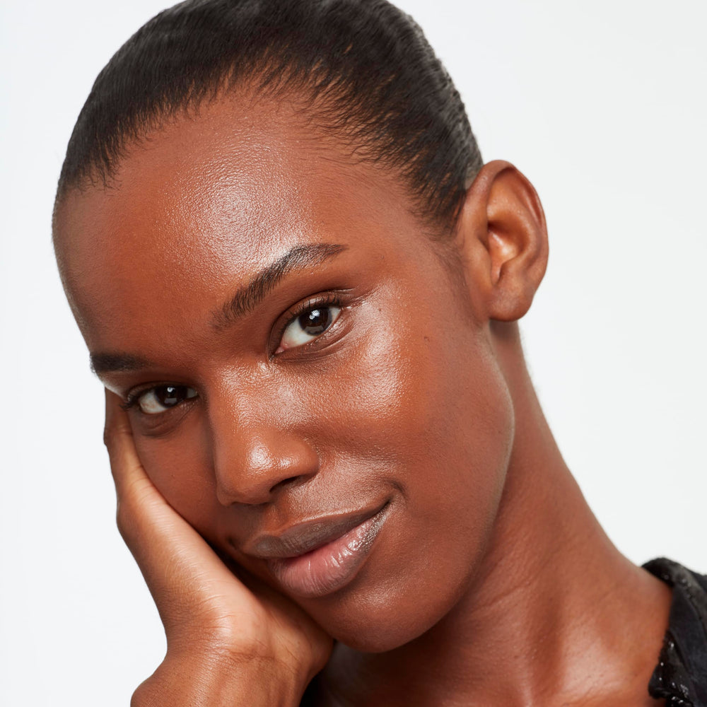 Application shot of Saie Glowy Super Skin Tint swirled on skin for natural glow.