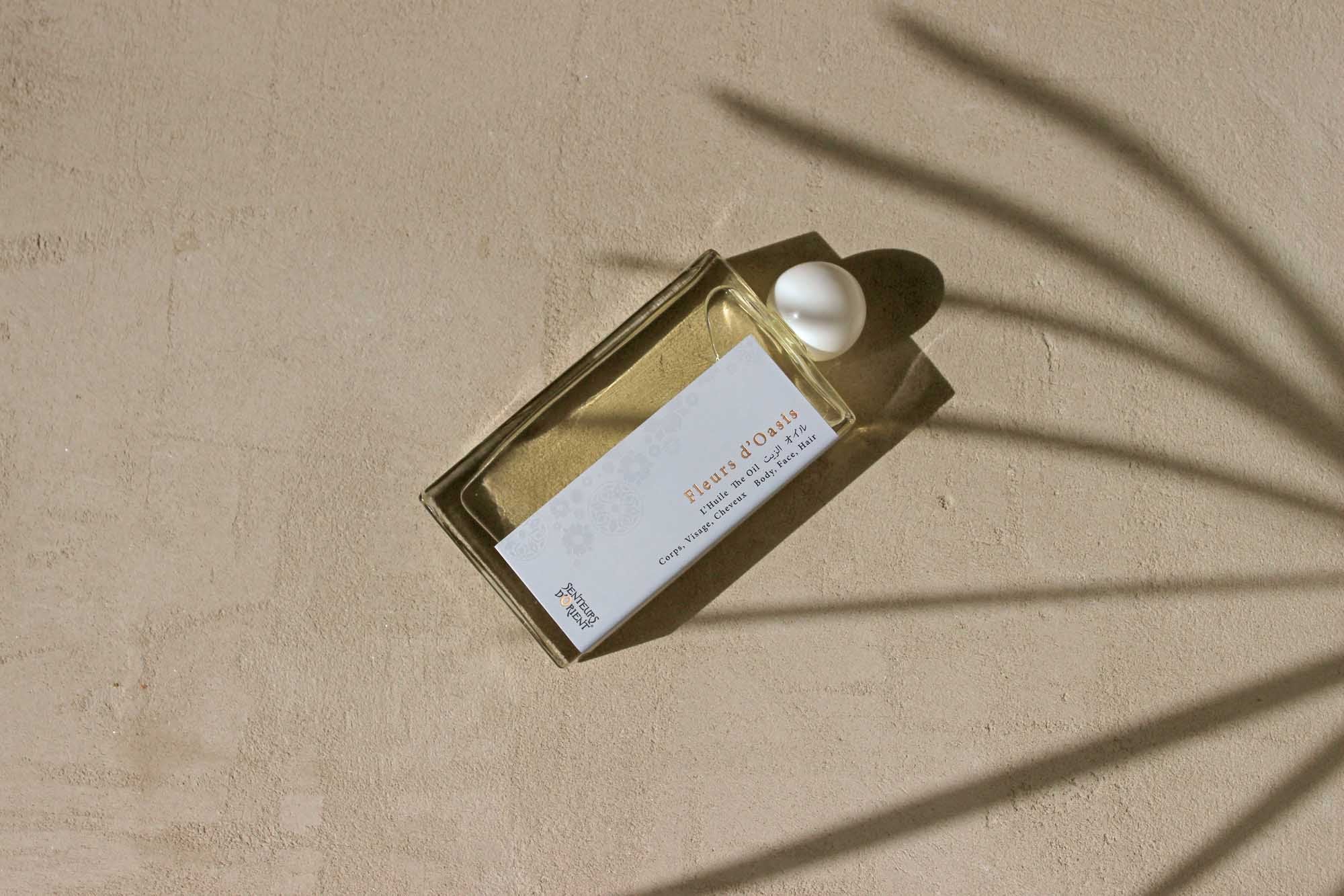 Hands applying Fleurs d'Oasis for radiant skin and hair shine.