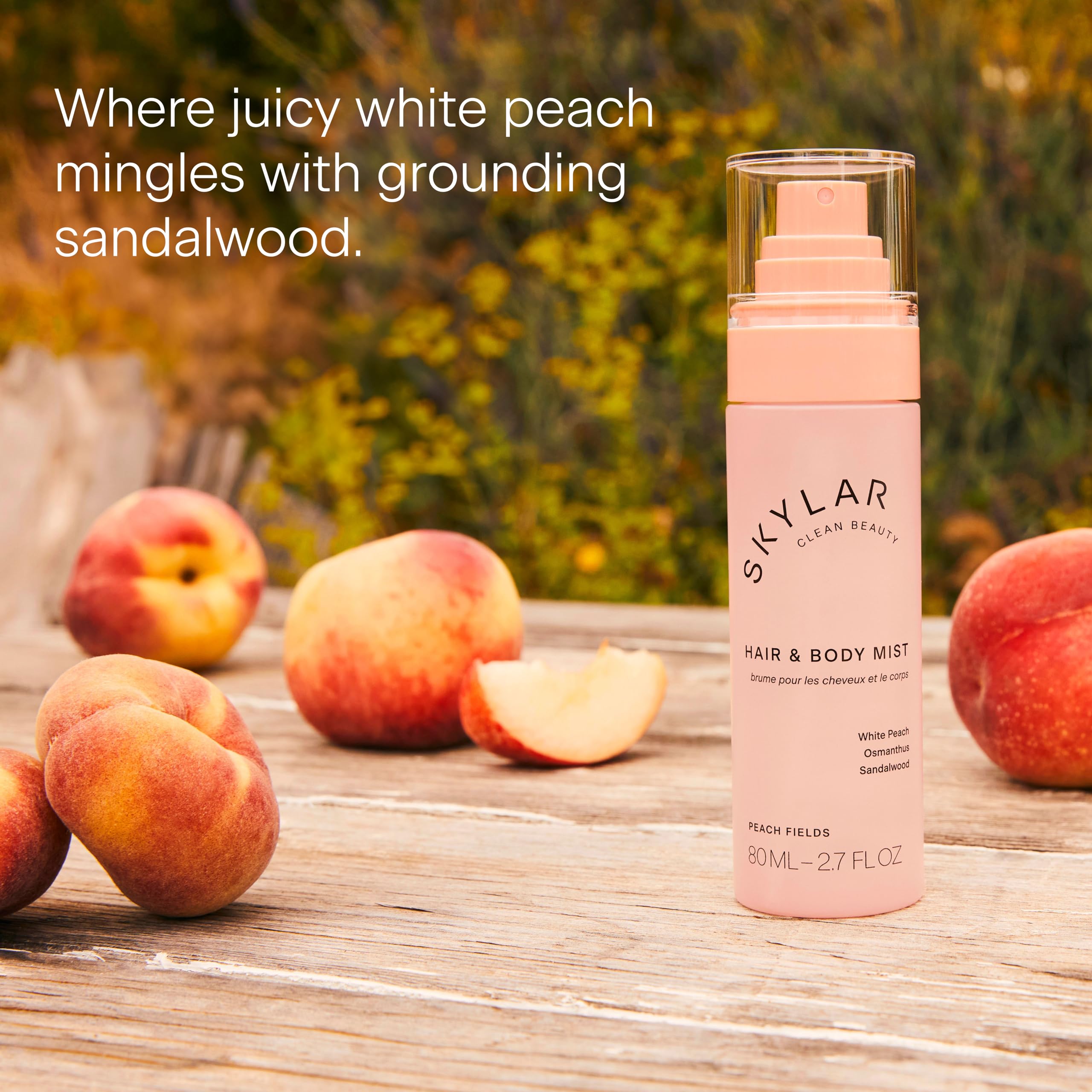 The Skylar Peach Fields bottle sits beside peaches in warm sunlight.