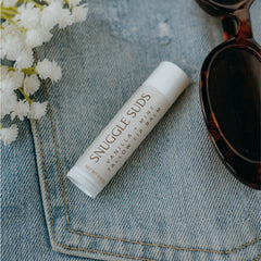 Snuggle Suds lip balm application close-up for smooth, non-greasy hydration.