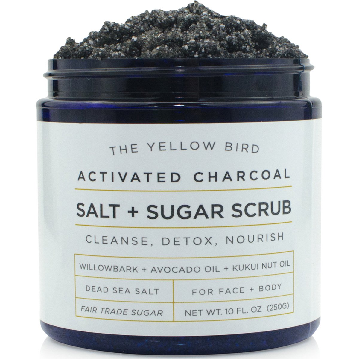 The Yellow Bird activated charcoal scrub jar closeup highlighting natural oils for smooth skin.