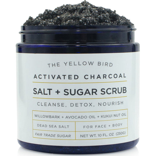 The Yellow Bird activated charcoal scrub jar closeup highlighting natural oils for smooth skin.