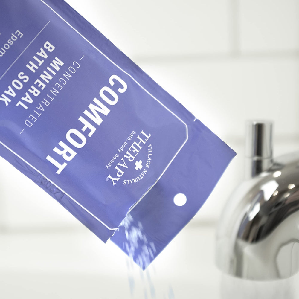 Village Naturals Therapy Comfort Mineral Bath Soak in a cozy bathroom scene for self-care.